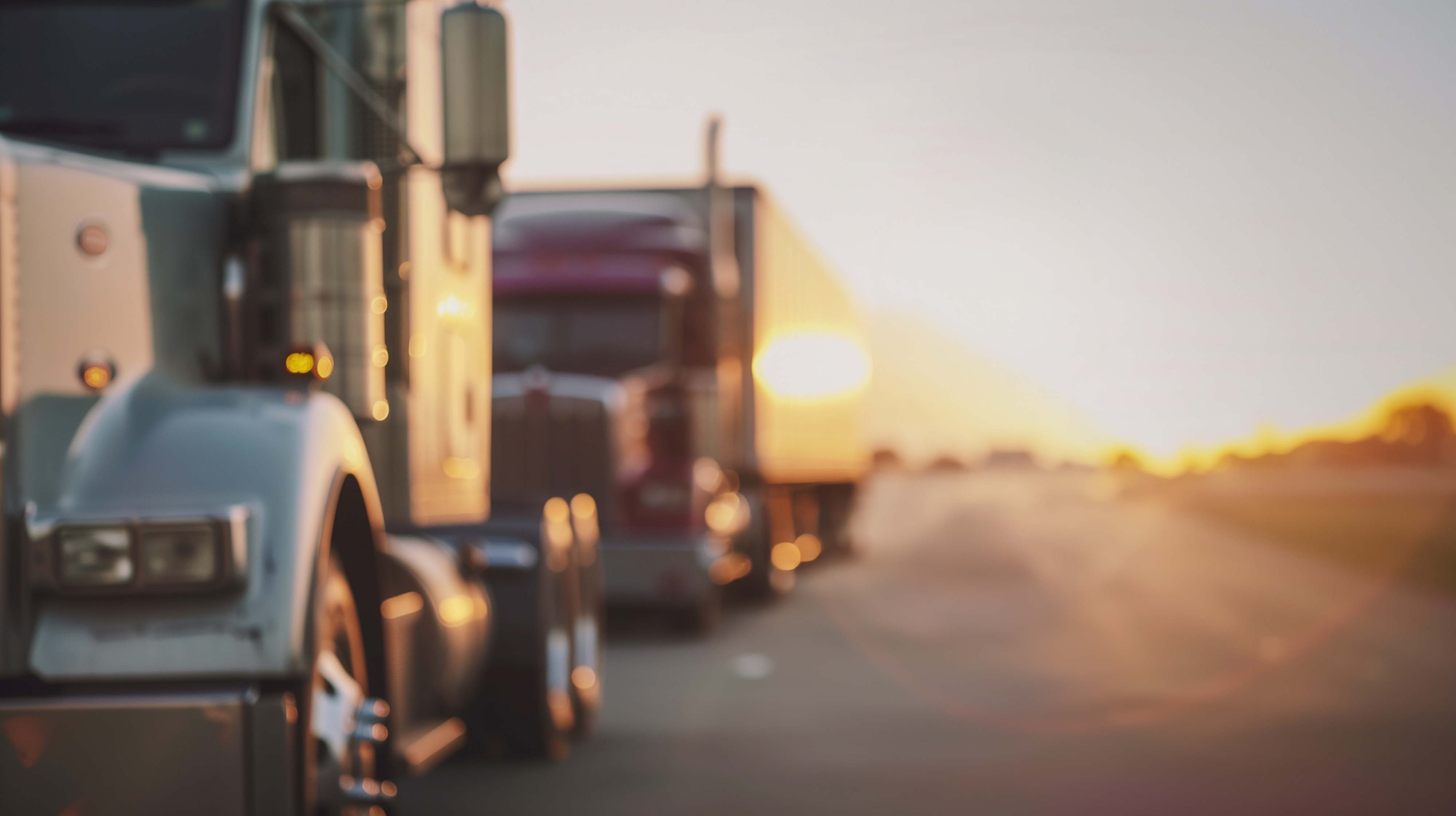Blurred image of two semi-trucks during a sunset