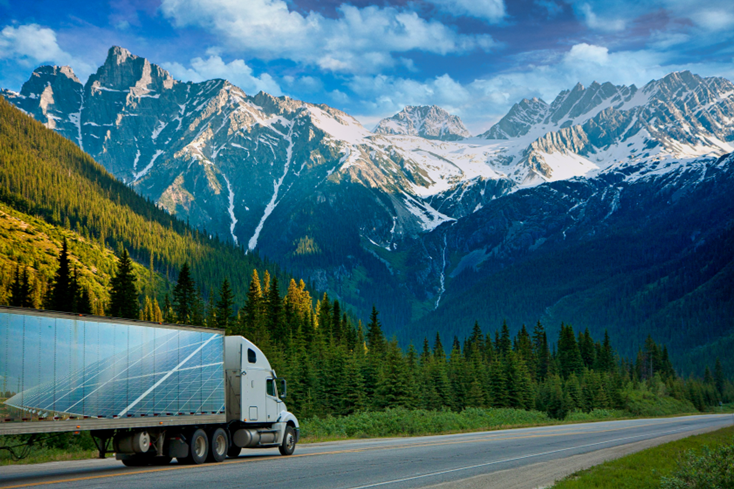 Solar powered semi truck on highway beside snowy mountains